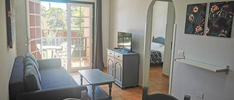 Un espace de vie compact comprenant un canapé, une table à manger et une petite kitchenette.