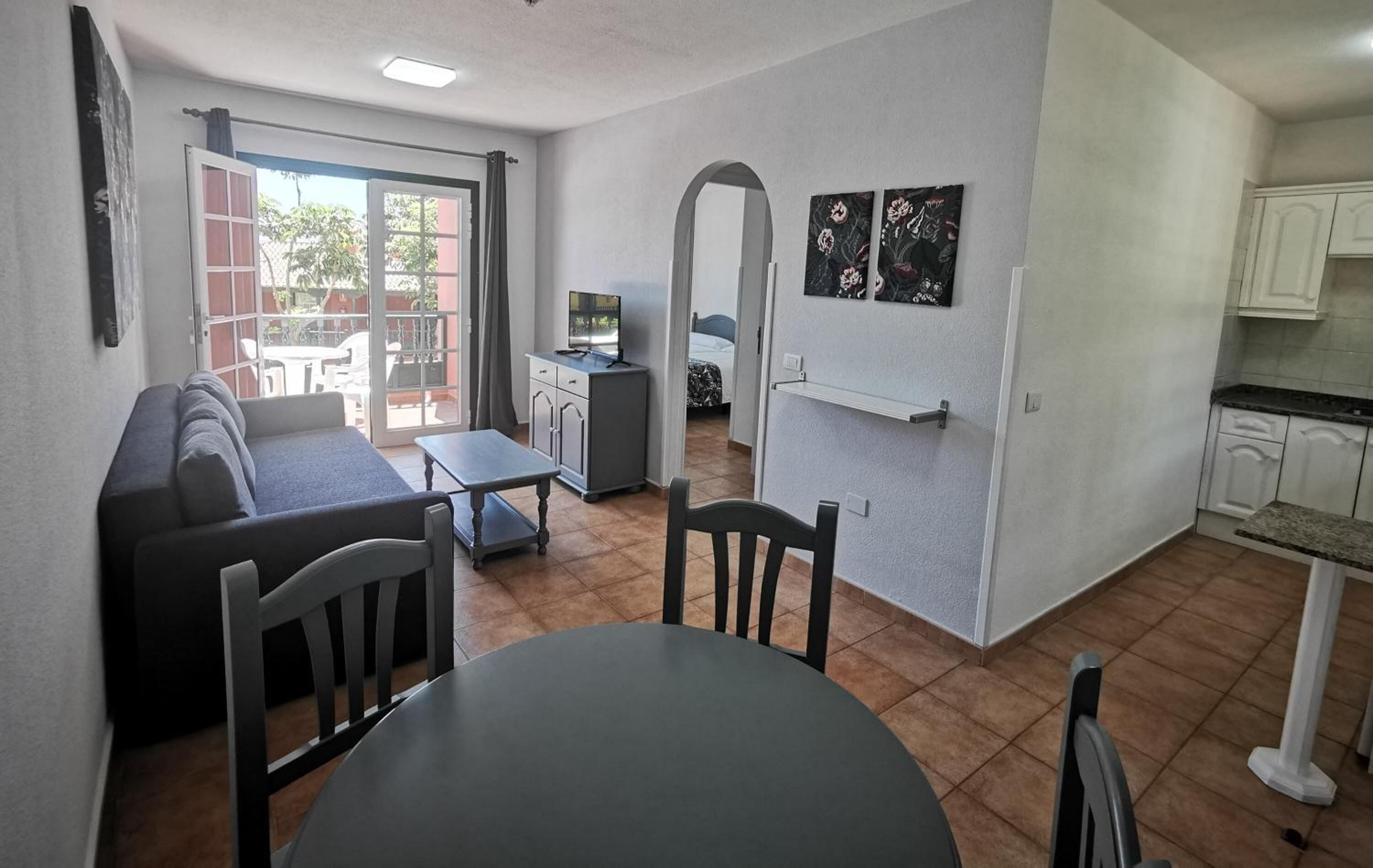 Un espacio habitable compacto con sofá, mesa de comedor y kitchenette.