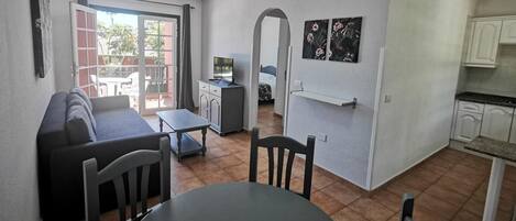 Un espacio habitable compacto con sofá, mesa de comedor y kitchenette.