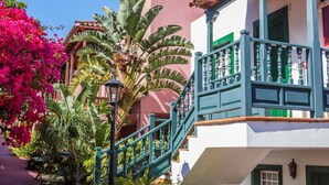 A building with a white facade, green shutters, and a balcony with a green railing. - Apartamentos Oasis San Antonio (Brena Baja)
