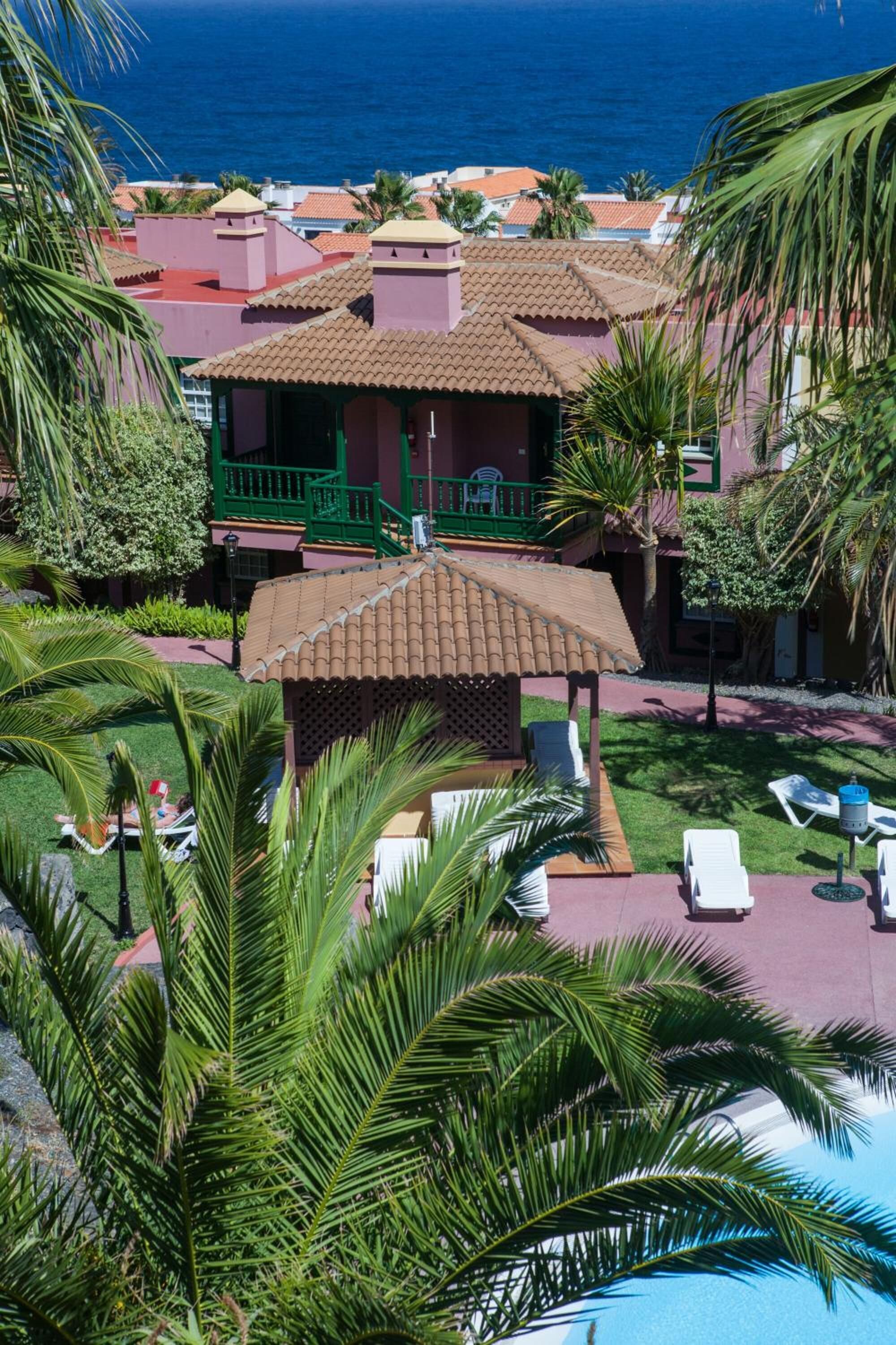 A resort with a pool area, lounge chairs, and a view of the ocean.