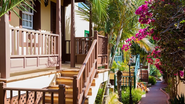 A pathway flanked by wooden railings and lush greenery, leading to a building with a balcony. - Apartamentos Oasis San Antonio (Brena Baja)