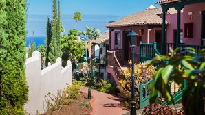 A coastal building with a red-tiled roof, a white wall, and a green railing. - Apartamentos Oasis San Antonio (Brena Baja)