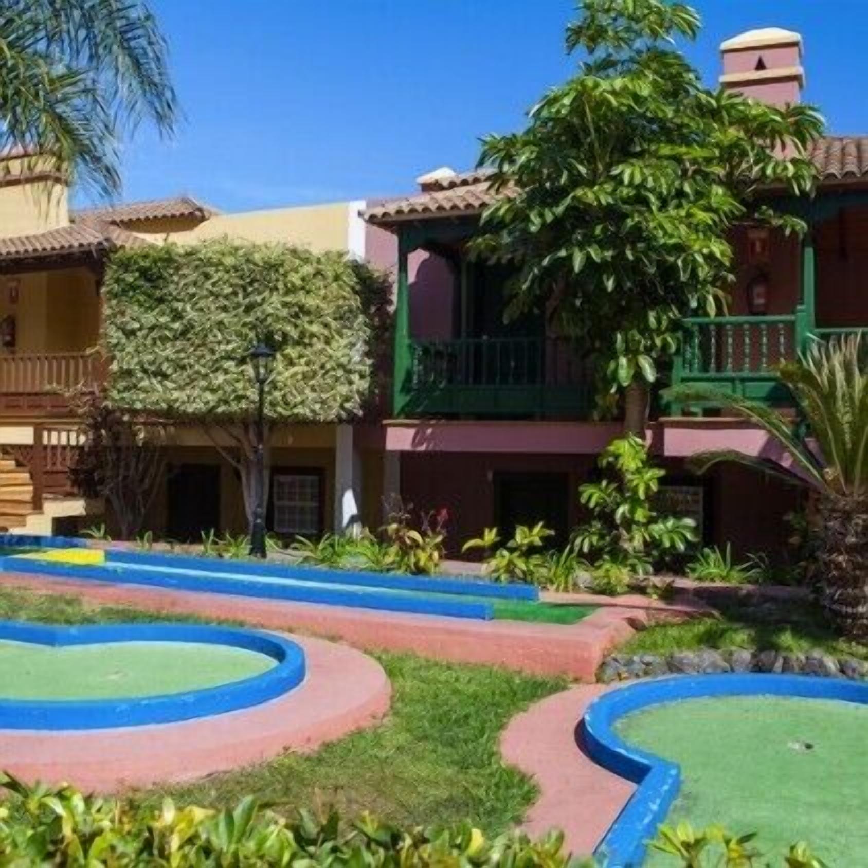Un patio con piscina, rodeado de edificios con balcones y vegetación.