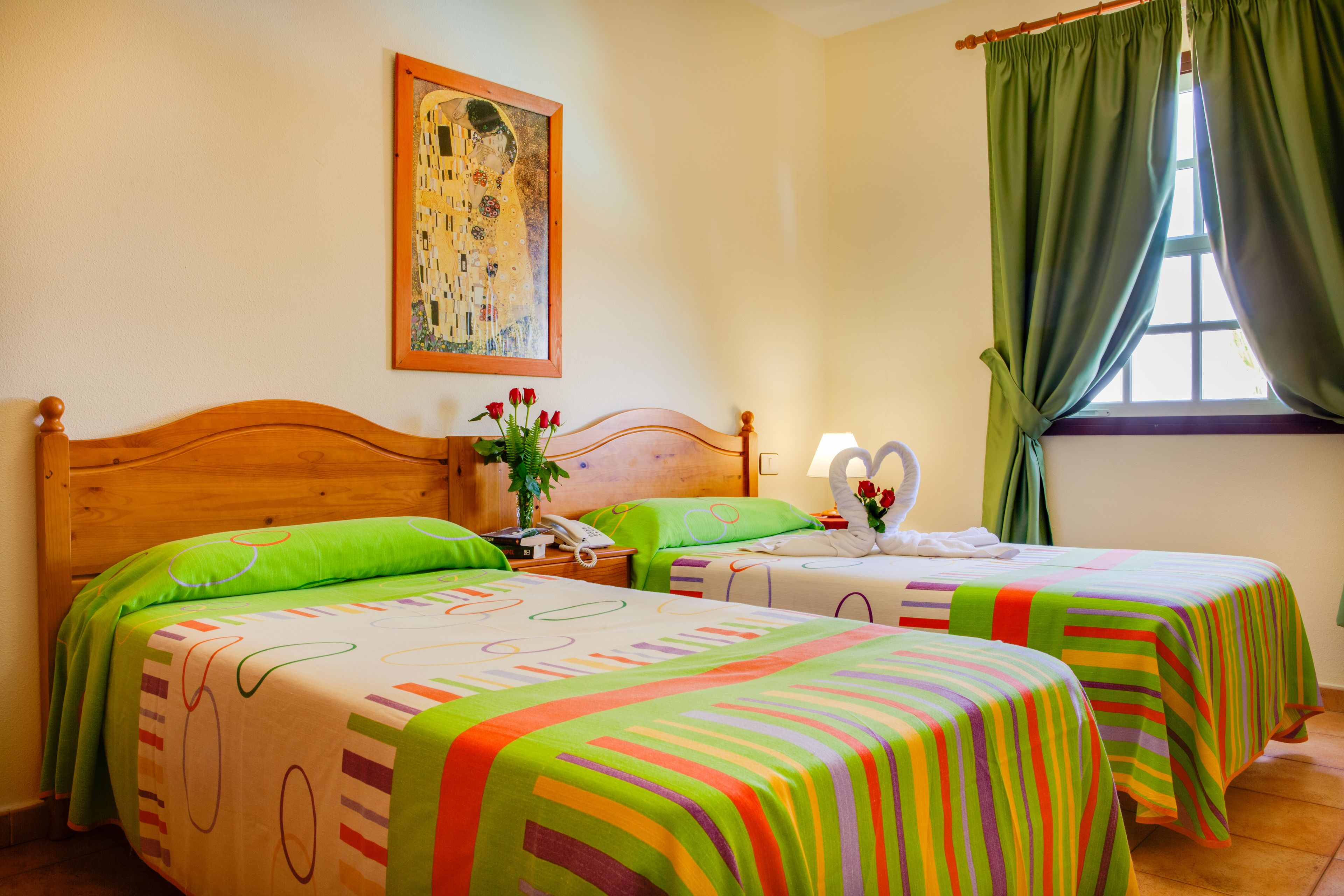 Habitación de hotel con dos camas, un cuadro en la pared y una ventana con cortinas.