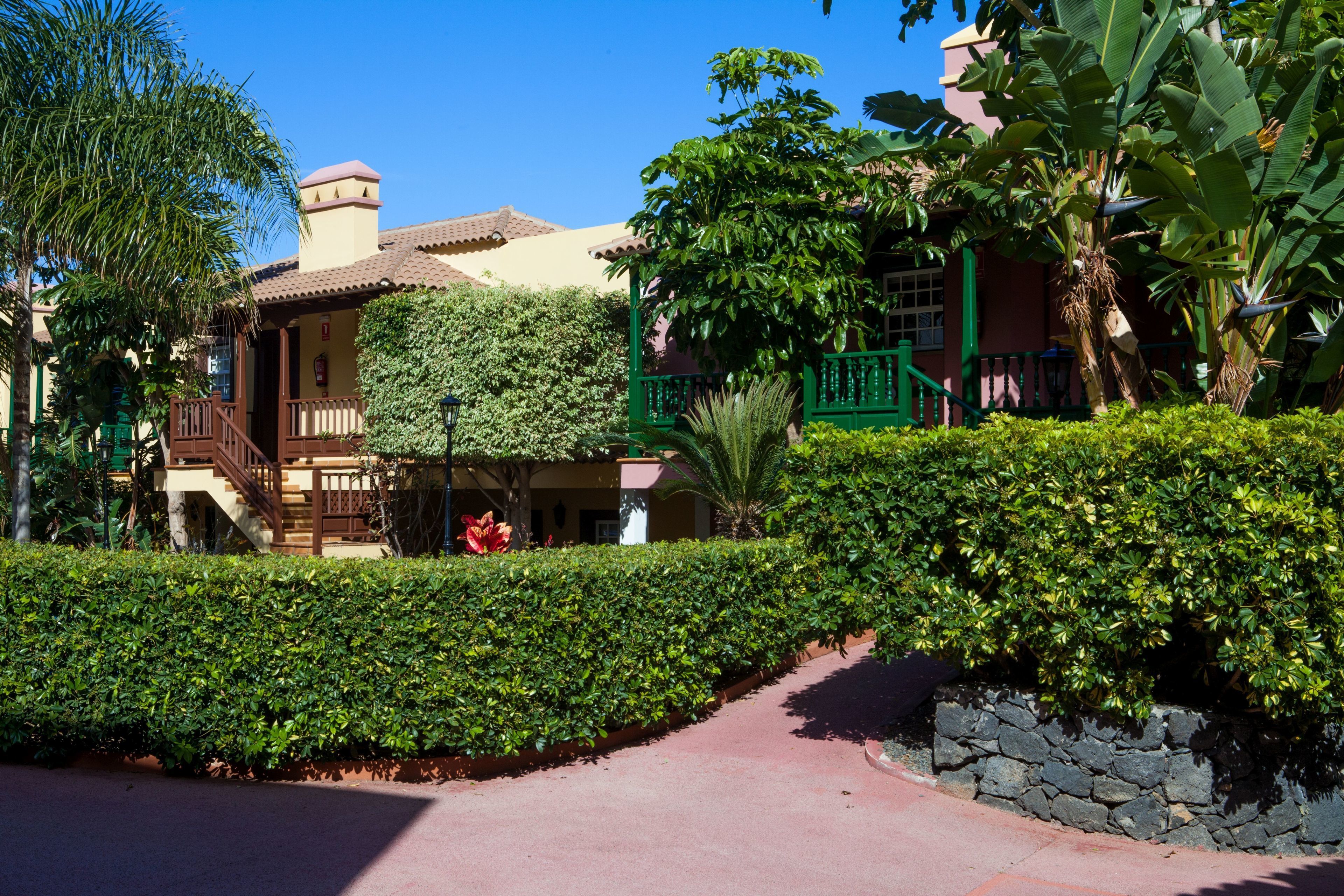 A building with a red-tiled roof, a green balcony, and a stone wall.