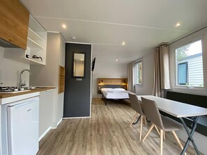 A compact room with a kitchenette, a bed, and a dining area.