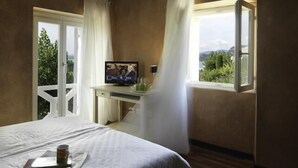 Ein Schlafzimmer mit einem Bett, einem Fernseher auf einem Schreibtisch und einem Fenster mit Vorhängen.