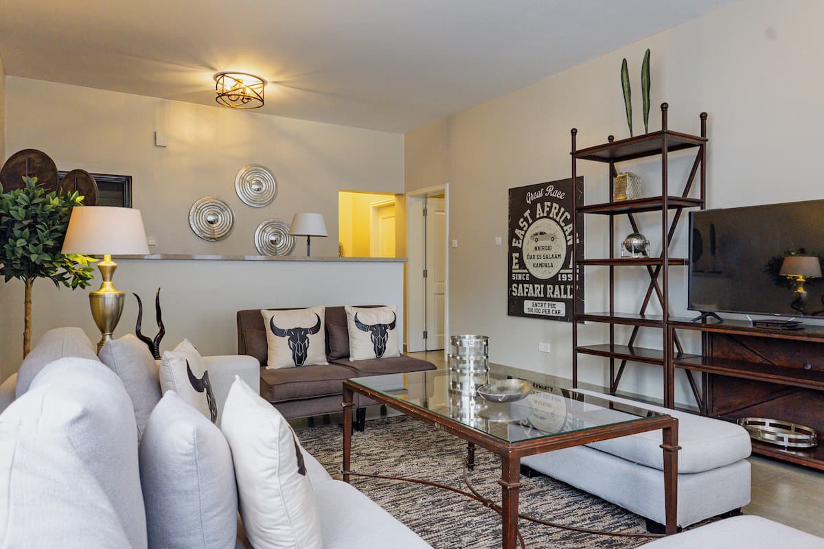A living room with a sofa, coffee table, TV, decorative wall art, and a bookshelf.