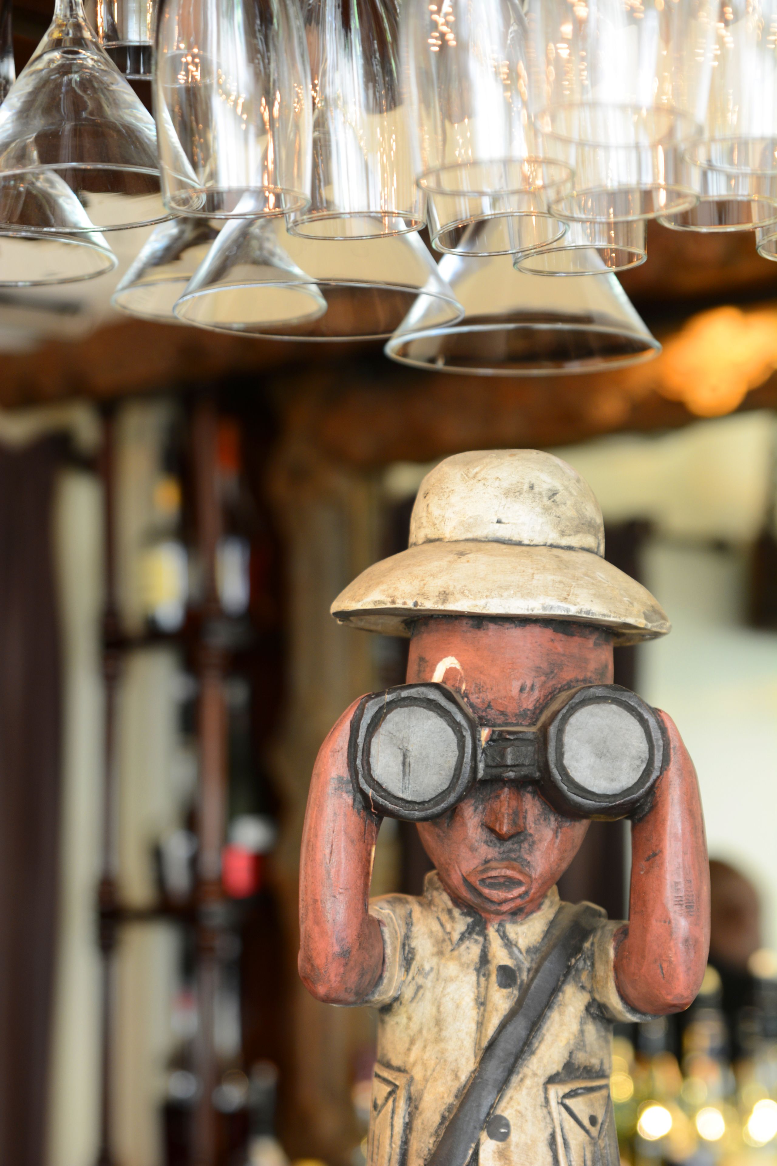 Um bar com uma estátua de madeira de um homem usando chapéu e óculos.