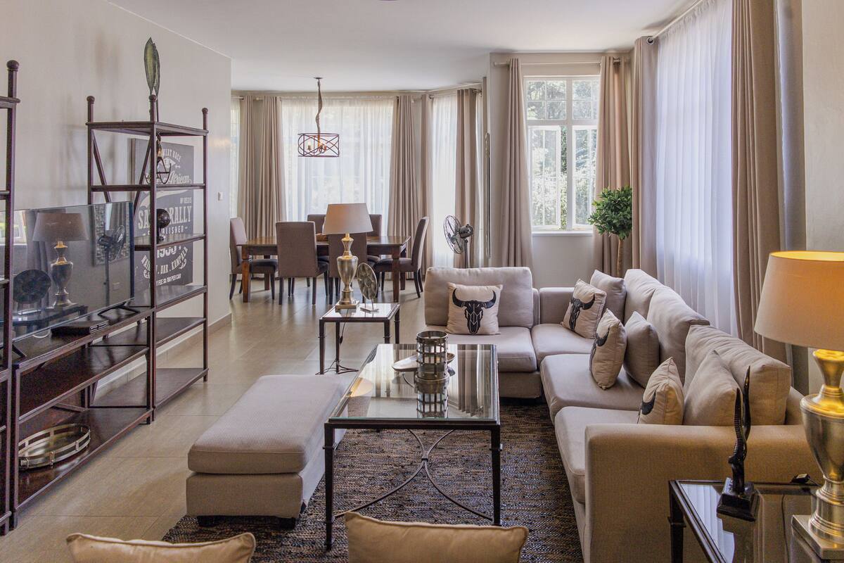 A modern living room with a sofa, ottoman, coffee table, and a glass display unit.