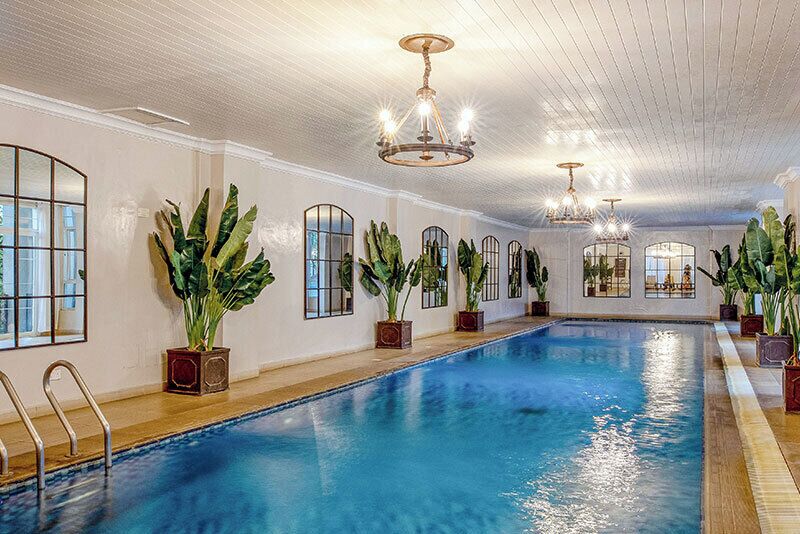 Una piscina techada, una piscina al aire libre, sombrillas