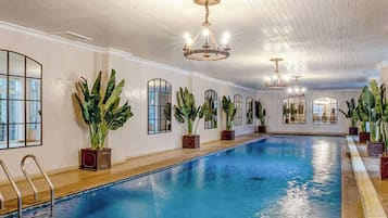 Una piscina techada, una piscina al aire libre, sombrillas