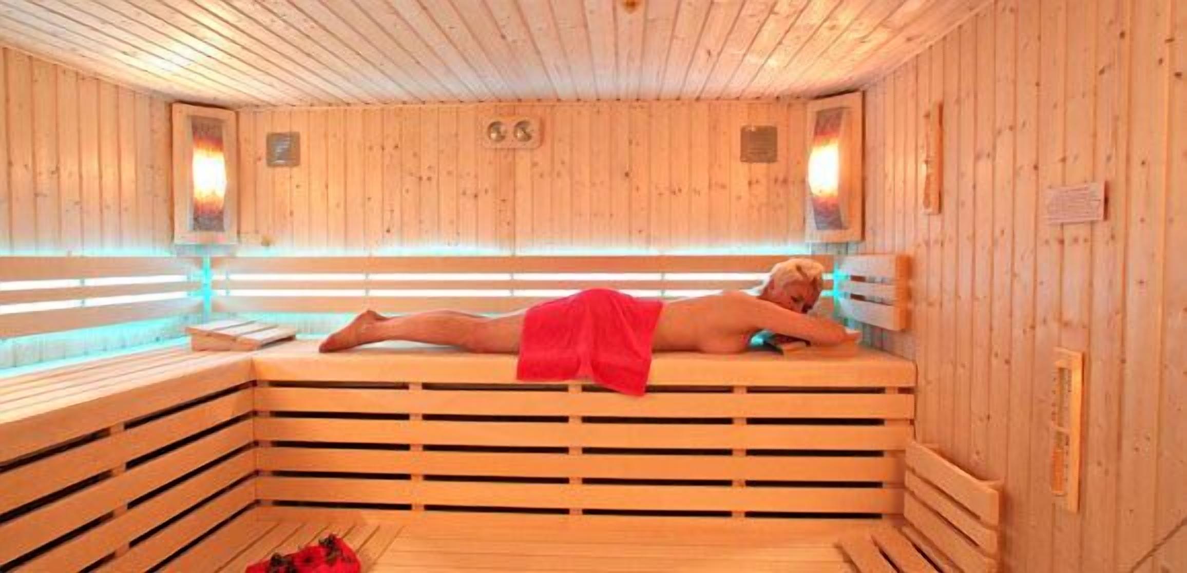 A sauna with wooden benches and a person lying down.