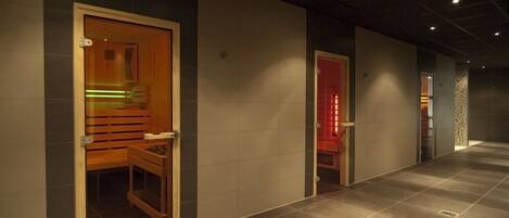A corridor with a wooden door leading to a room with a sauna, a red-lit door, and a patterned wall.