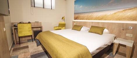 A hotel room with a bed, a desk, a chair, and a large window.
