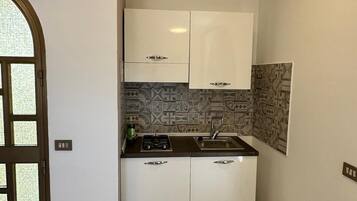 A kitchen with white cabinets, a gas stove, and a sink.