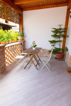 A patio with a wooden table and chairs, potted plants, and a brick wall with a lattice design. - B&B Sicily In Love (Taormina)