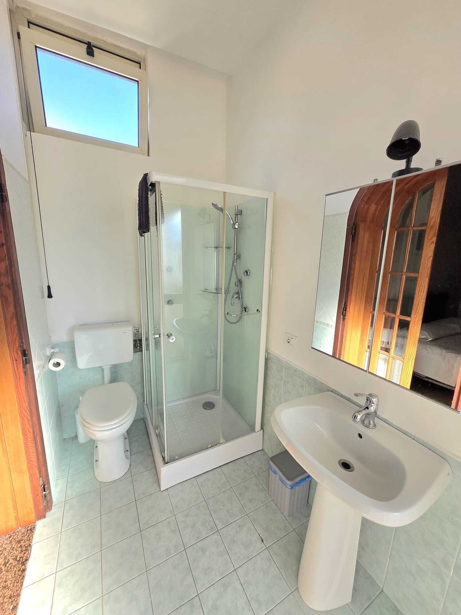 Un baño con ducha de vidrio, inodoro y lavamanos.