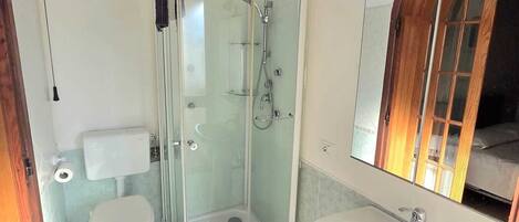 Un baño con ducha de vidrio, inodoro y lavamanos.