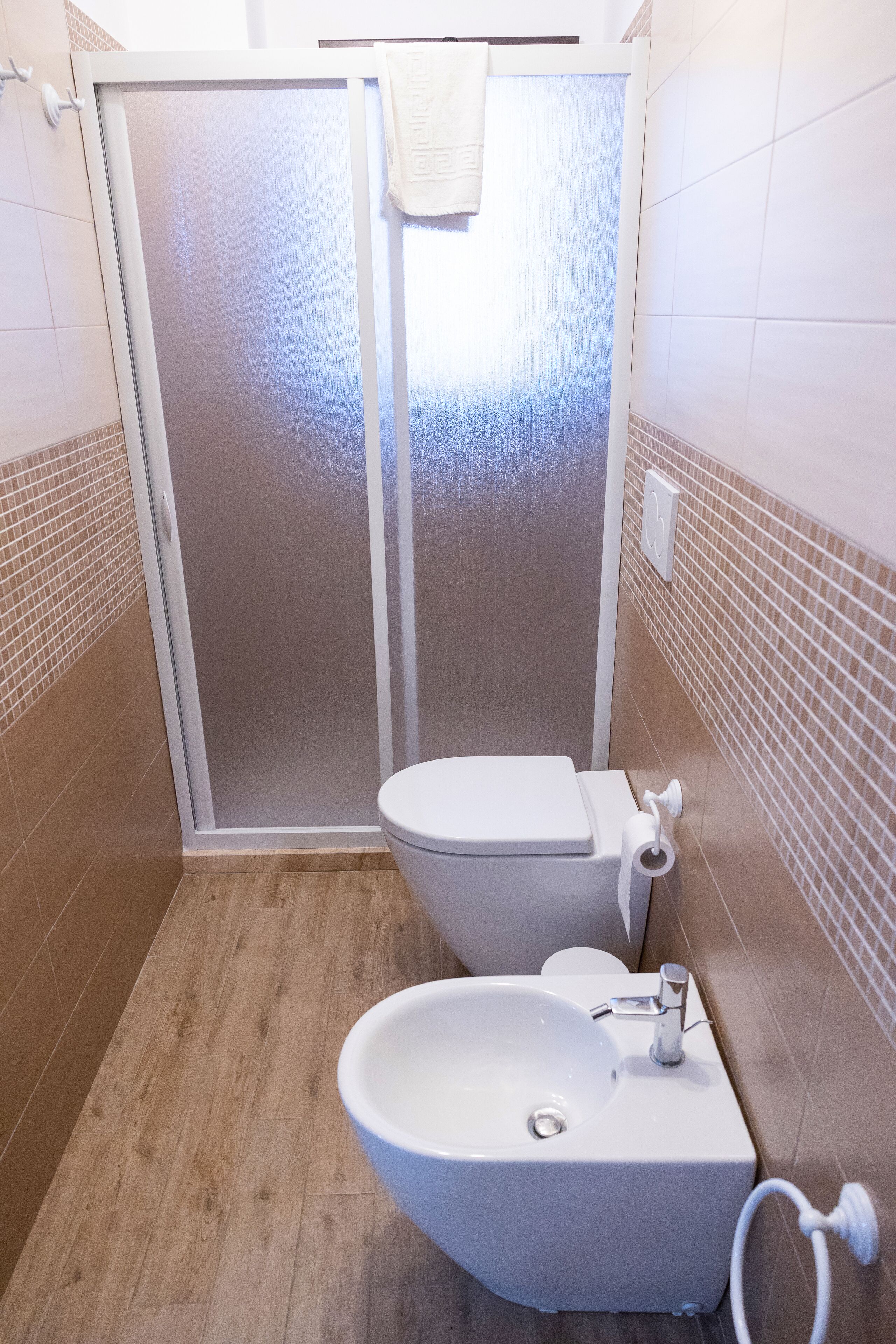 A bathroom with a shower enclosure, a toilet, and a sink.