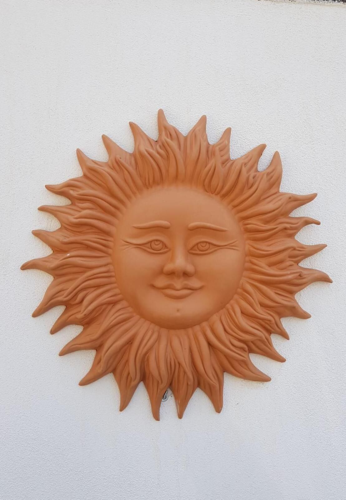 A wall-mounted sun sculpture with a stylized face.
