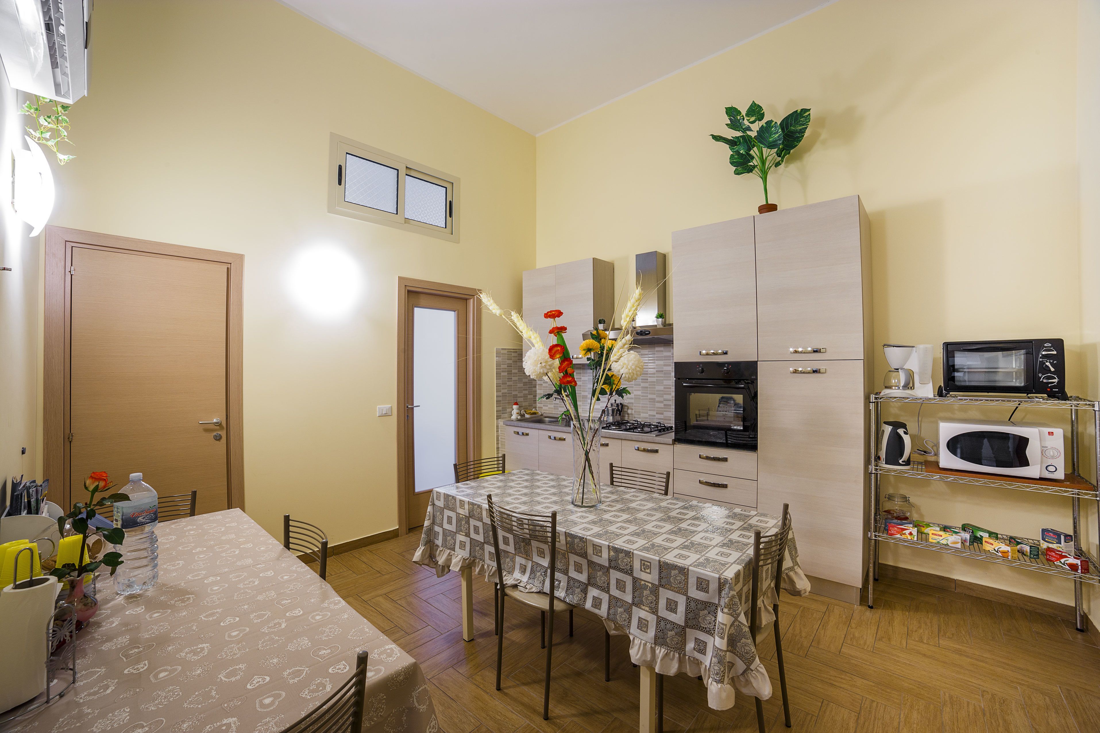 A compact kitchen with a dining table, chairs, a microwave, a stove, and a small refrigerator.