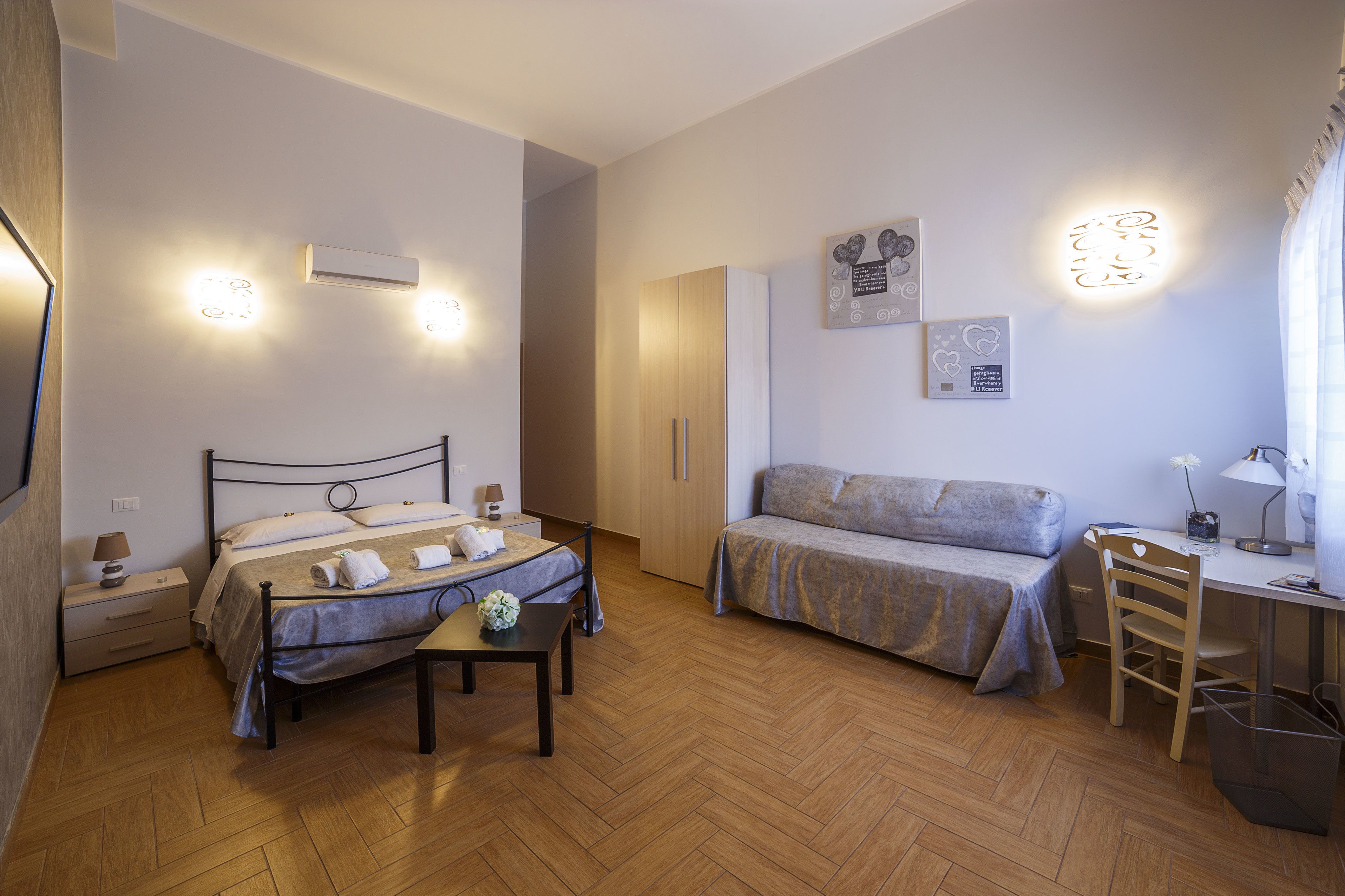 A bedroom with a bed, a desk, a chair, and a small table.