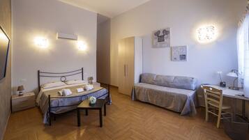 A bedroom with a bed, a desk, a chair, and a small table.