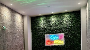 Une salle de spa équipée d’un jacuzzi, de deux fauteuils blancs rembourrés, d’un néon et d’un mur à texture.