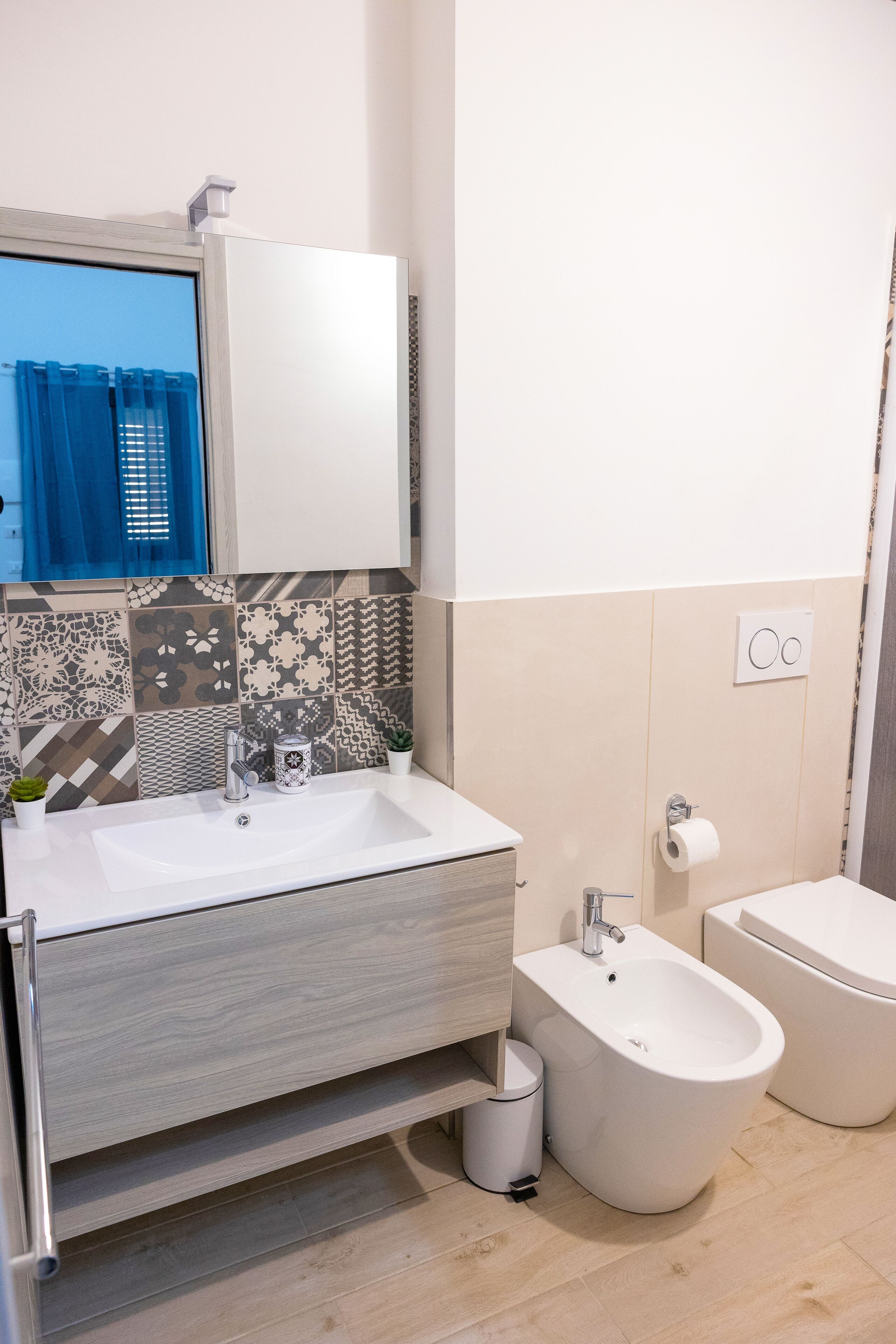 Un baño moderno con un lavabo blanco, un bidé y un espejo sobre el lavabo.