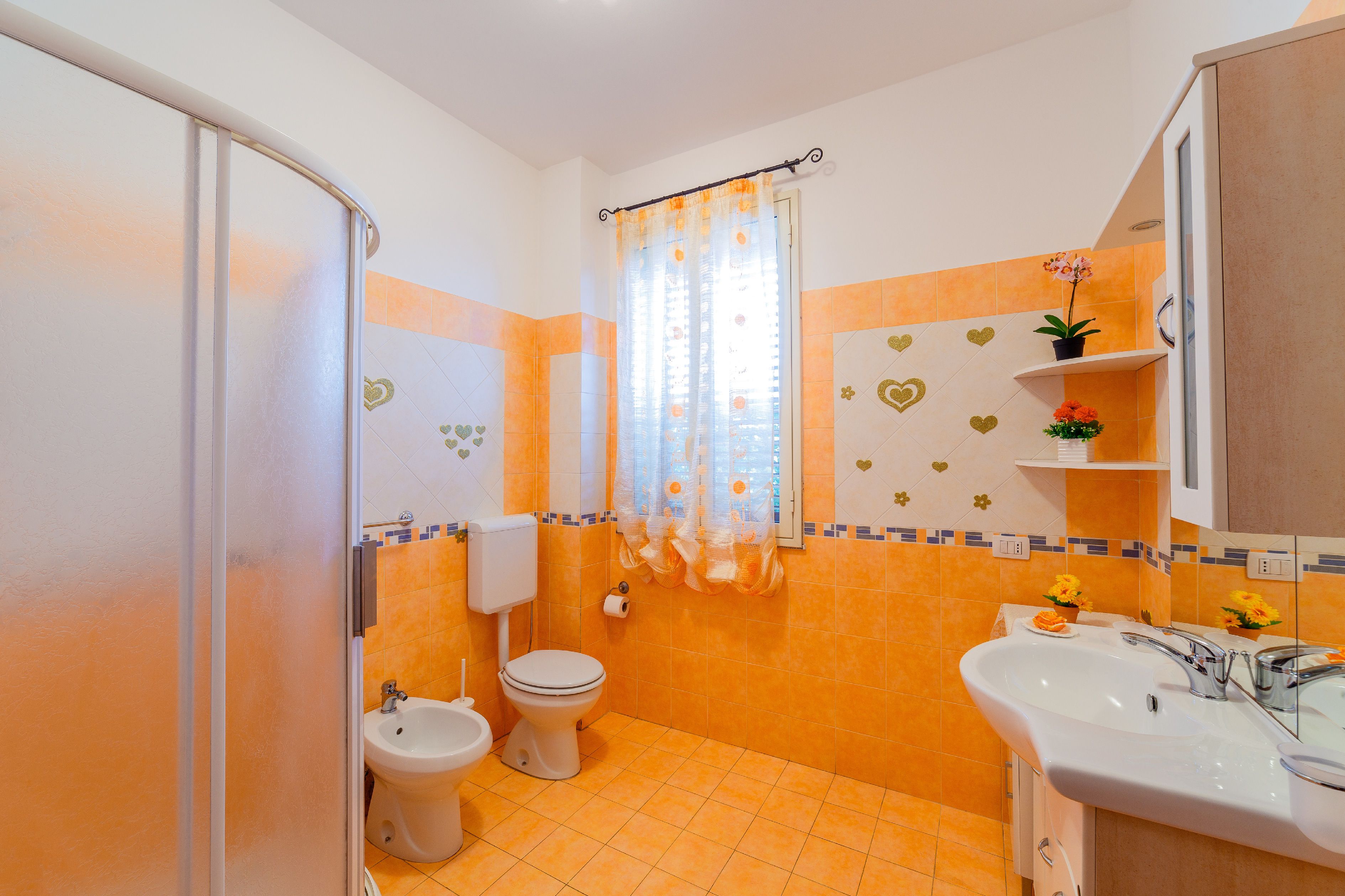 A bathroom with a shower, toilet, bidet, and sink.
