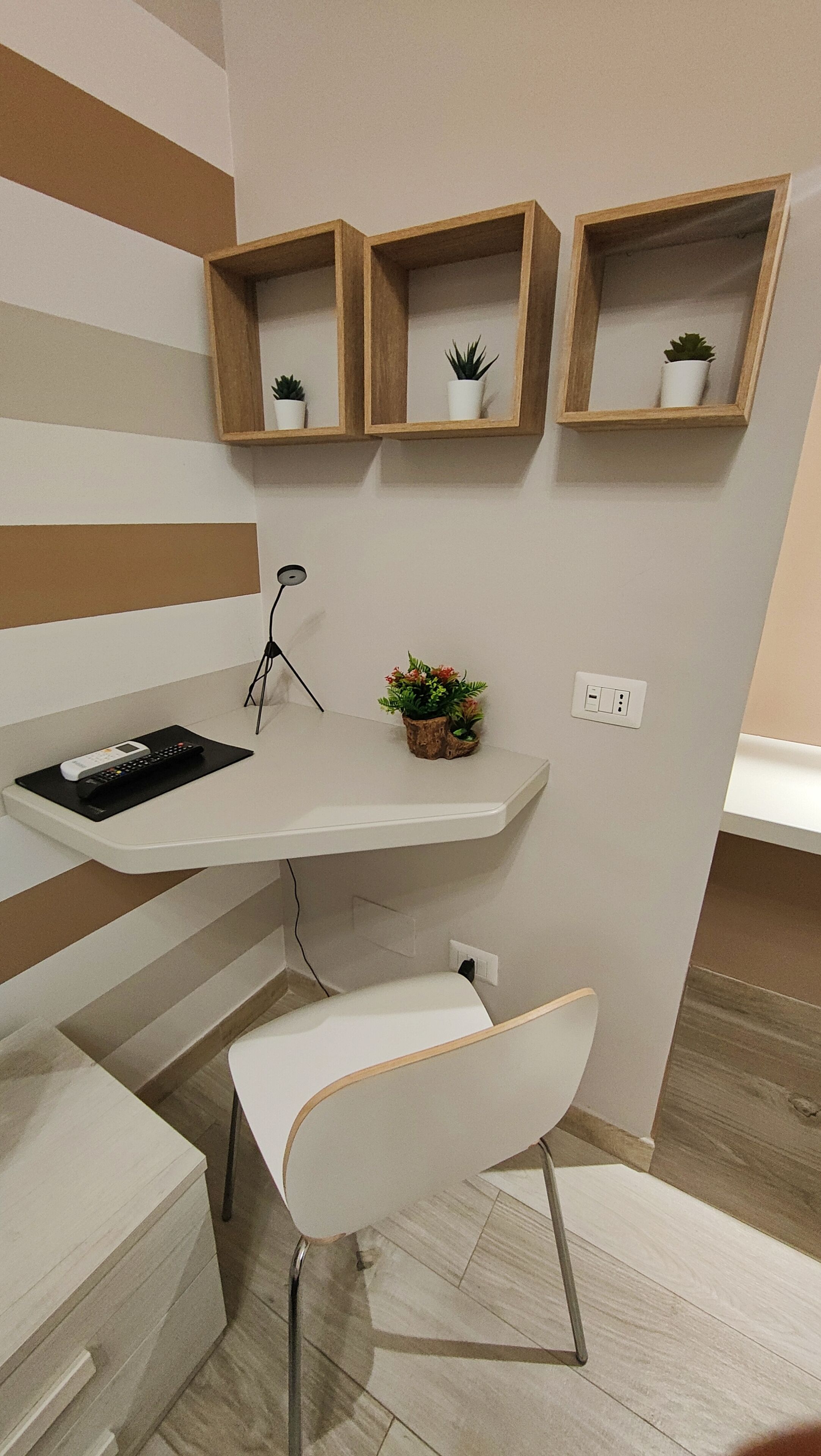 A modern kitchen with a white countertop, a built-in sink, and wooden shelves above.