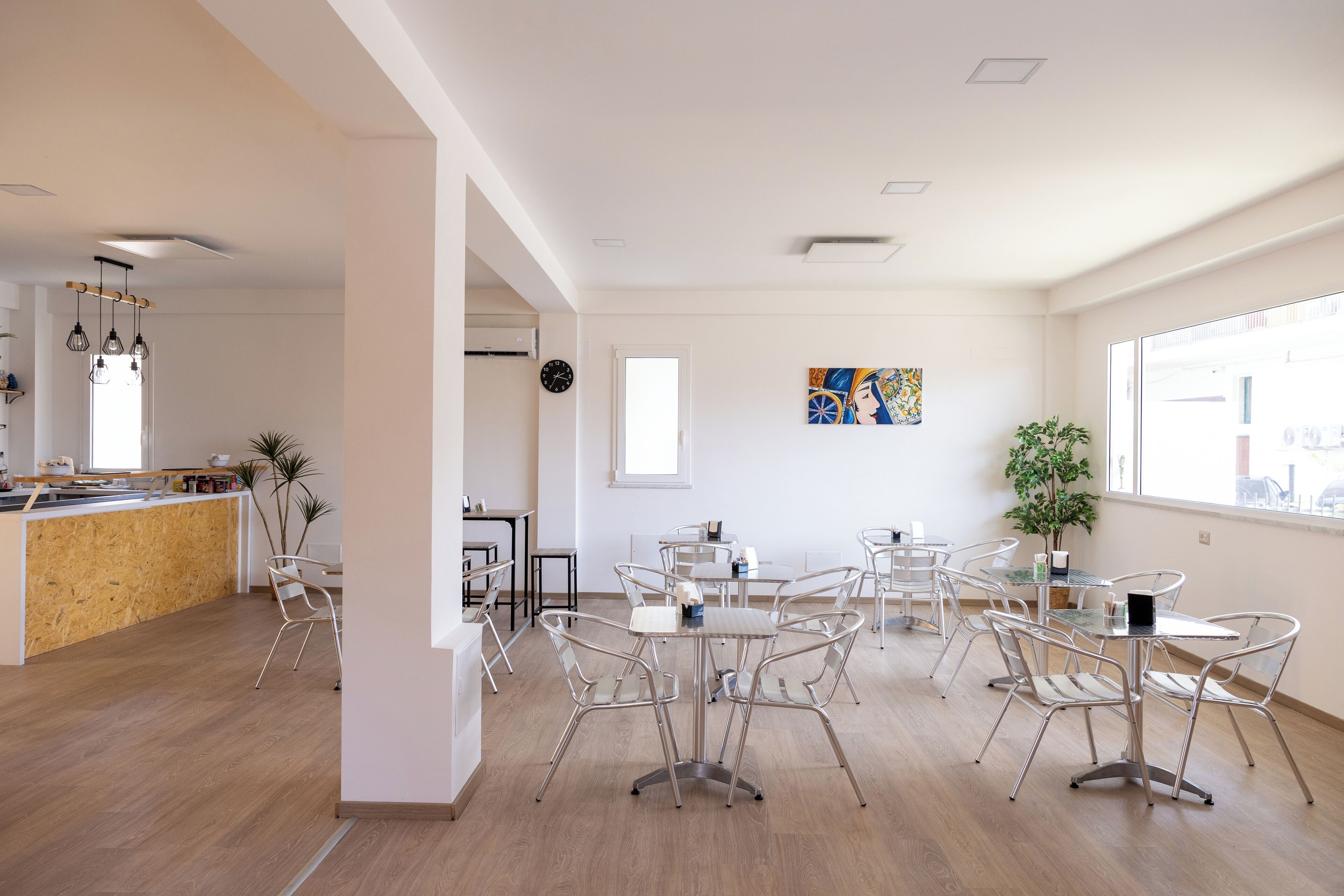 A modern interior with a kitchen area, dining tables, and chairs.