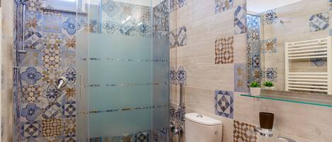 Un baño moderno con ducha envuelta en vidrio, inodoro y lavamanos.