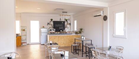 Une cuisine moderne avec un coin café, un espace repas doté de chaises et de tables en métal, et un plancher en bois.
