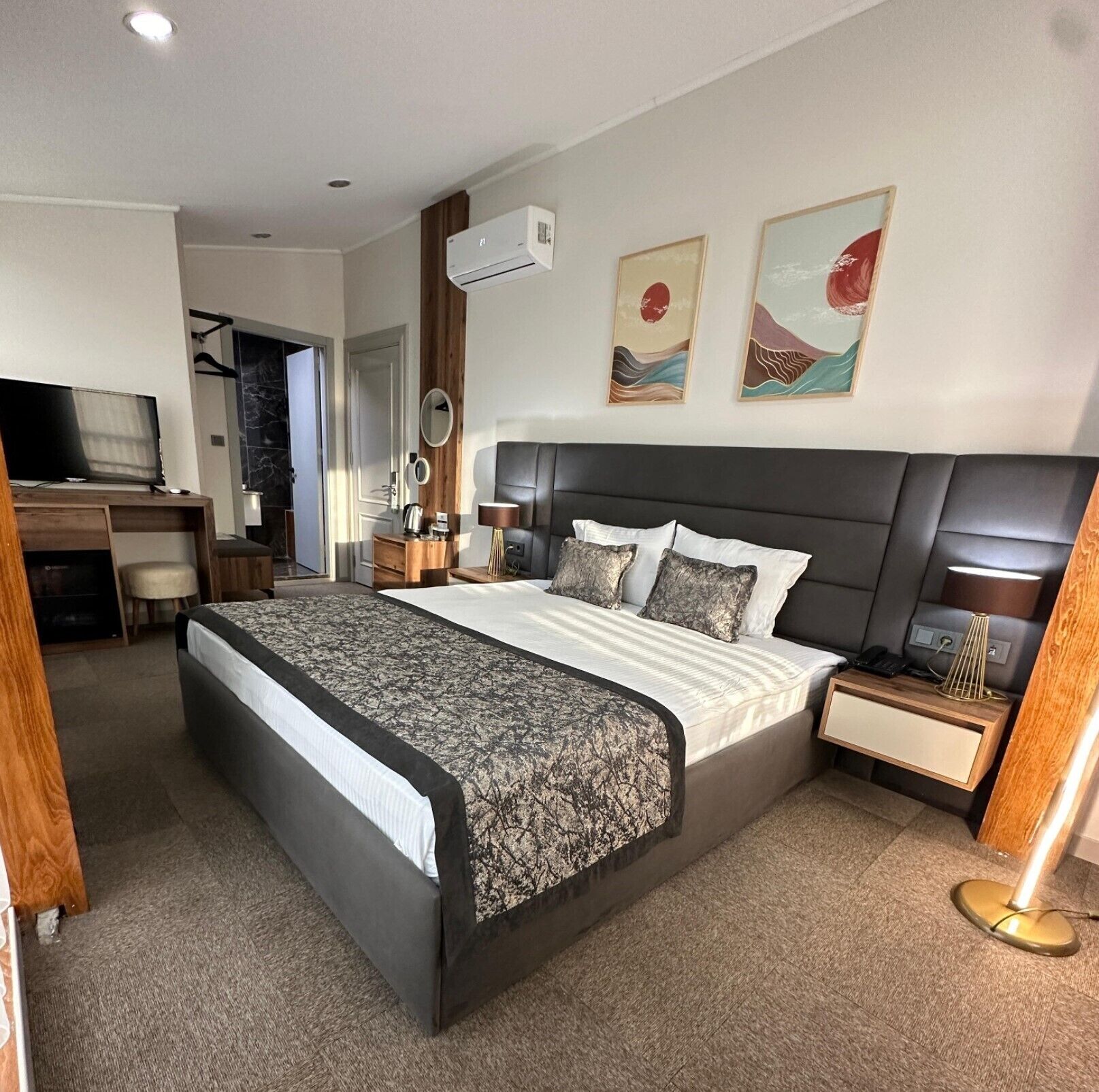 A modern hotel room with a large bed, a desk, a chair, and a TV.