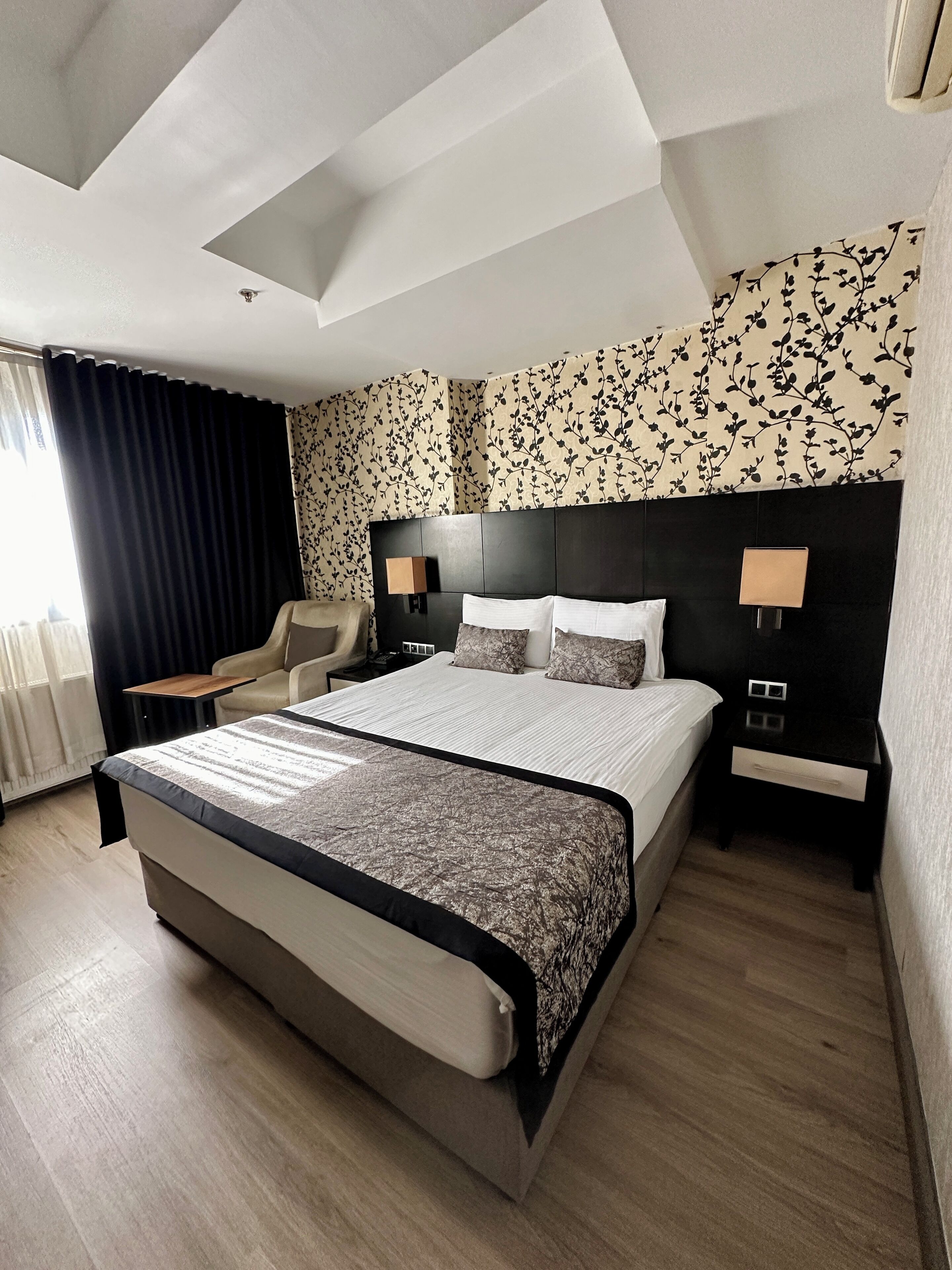 Una habitación de hotel moderna con una cama grande, un escritorio, una silla y una mesita de noche con lámparas.