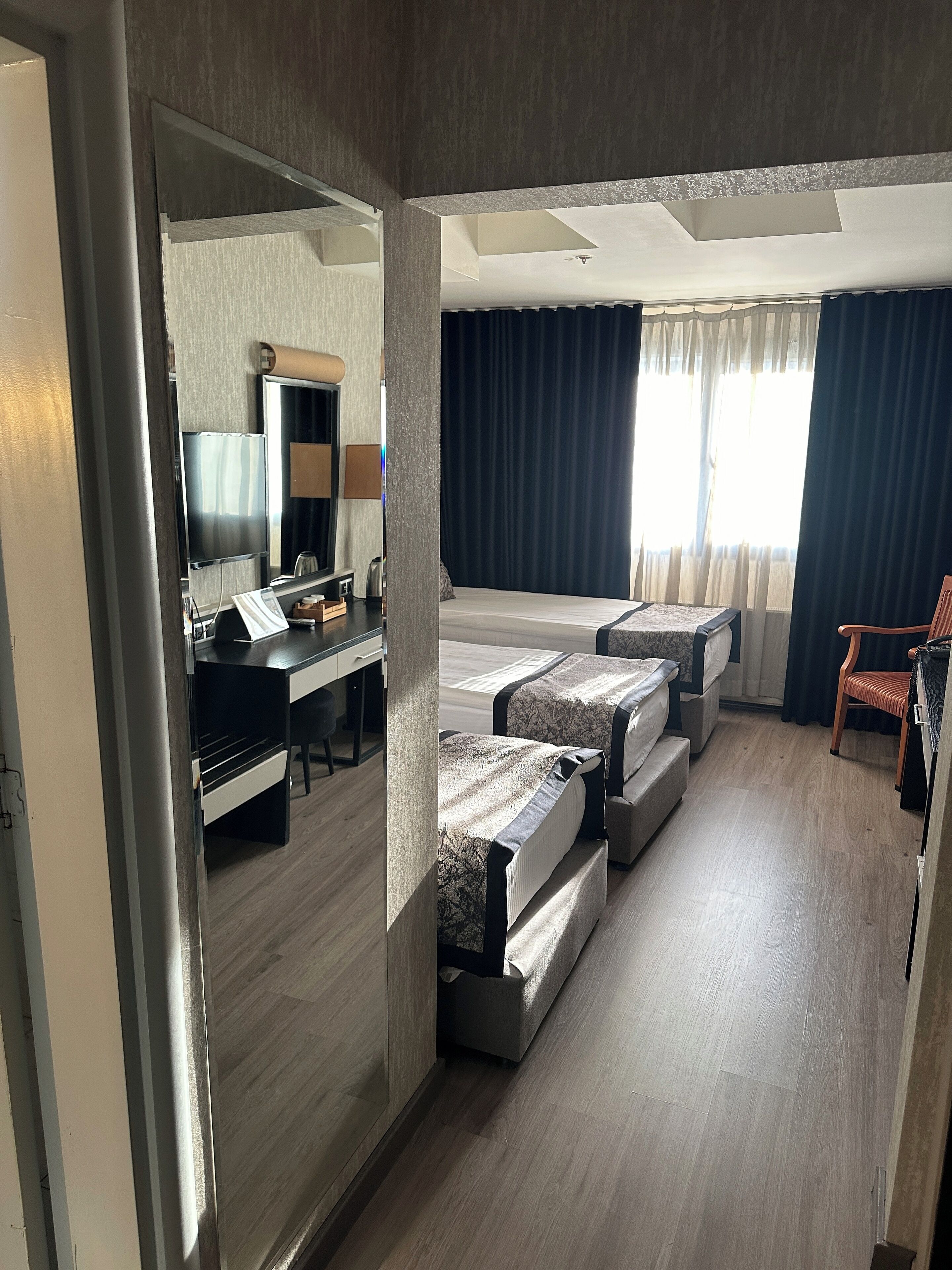 Una habitación de hotel con una cama, un escritorio, una silla y un espejo.