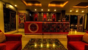 Un vestíbulo con mostrador de recepción, sofás rojos y una mesa de centro de vidrio decorativa.