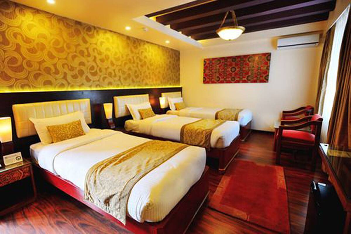 A hotel room with two beds, a red carpet, a wooden floor, a red chair, and a patterned wall.