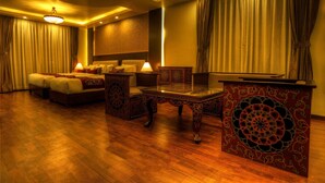 Una habitación de hotel con una cama grande, una sala de estar con una mesa y un televisor.