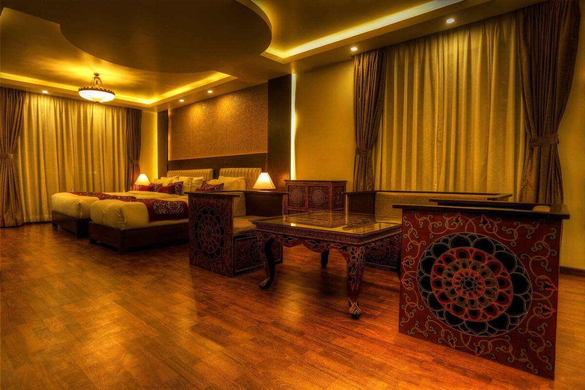 A hotel room with a large bed, a sitting area with a table, and a television.