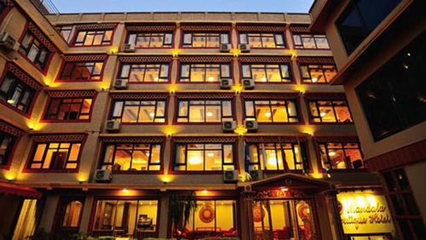 Un hotel de varios pisos con diseño arquitectónico tradicional, que cuenta con varios balcones y un patio central.