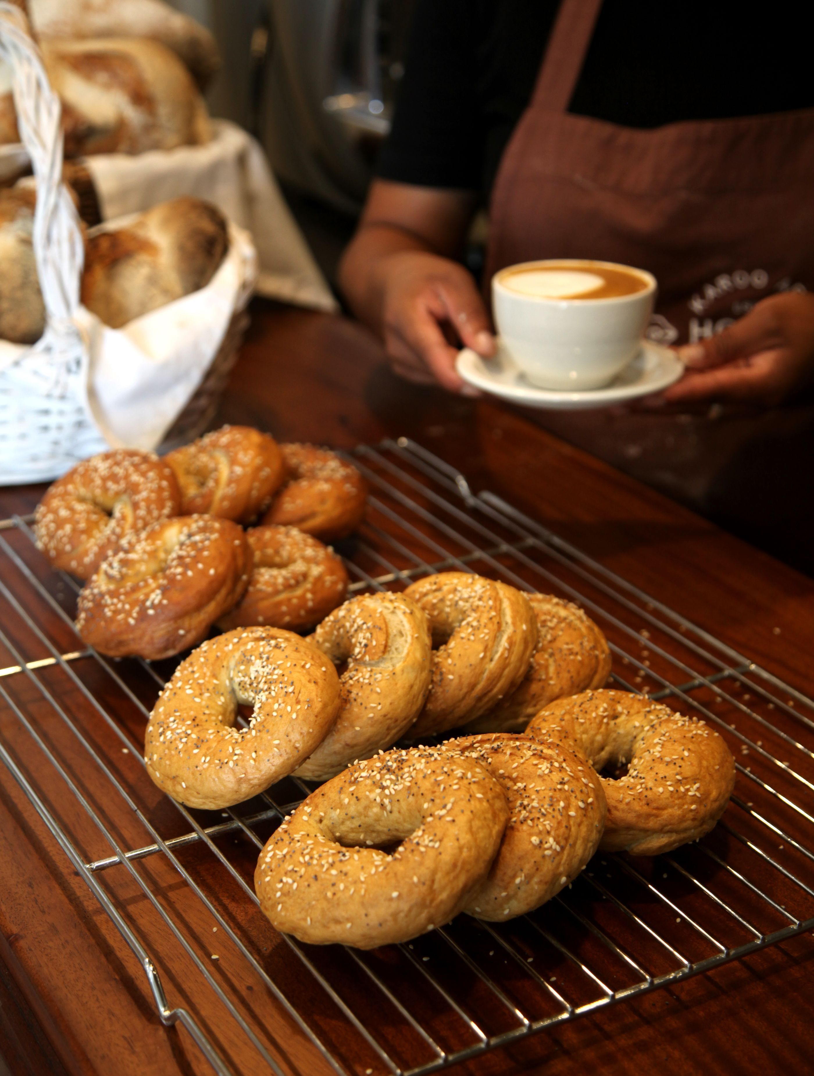 A tray of bagels with sesame seeds on a wire rack.
