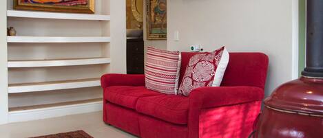 A living room with a red sofa, patterned rug, and a painting on the wall.