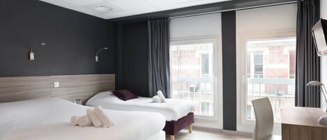 Quarto de hotel com duas camas, uma escrivaninha e uma cadeira.