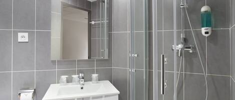 A modern bathroom with a glass-enclosed shower, a white sink, and a mirror above it.