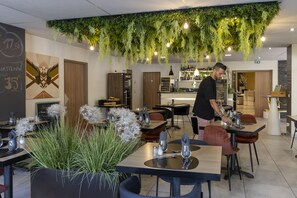 Ein modernes Restaurant mit hängenden Pflanzen, ordentlich angerichteten Tischen und einer Bar.