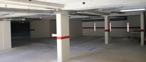 Un parking souterrain vide, avec des piliers en béton, un éclairage fluorescent et un intérieur propre et sans ornements.